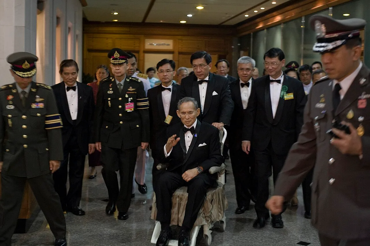 Król Bhumibol Adulyadej na wózku, w otoczeniu oficjeli i oficerów, 2010 rok