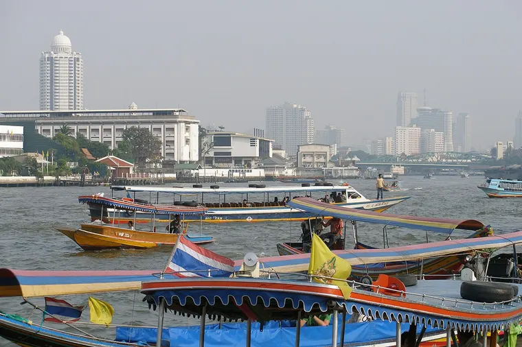 Kolorowe łodzie na rzece Chao Phraya, w tle panorama Bangkoku