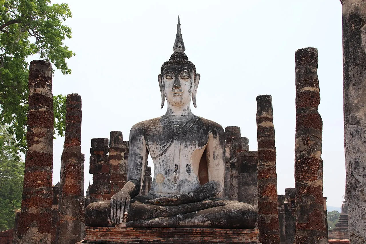 Posąg Buddy wśród ceglanych kolumn w parku historycznym Sukhothai