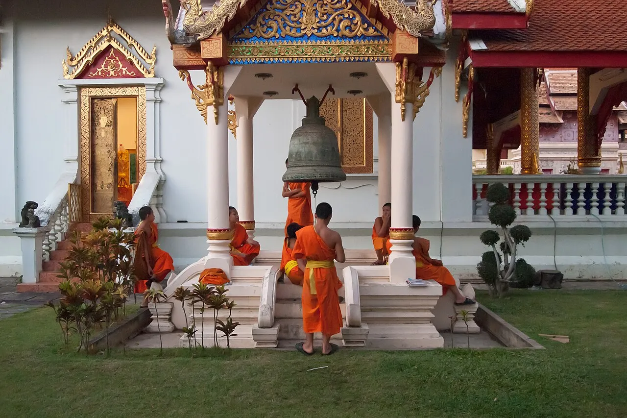Mnisi w pomarańczowych szatach przed świątynią w Chiang Mai