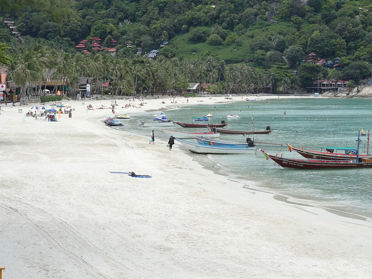 Szeroka plaża z białym piaskiem i łodziami longtail na Haad Rin Sunrise Beach na Ko Phangan