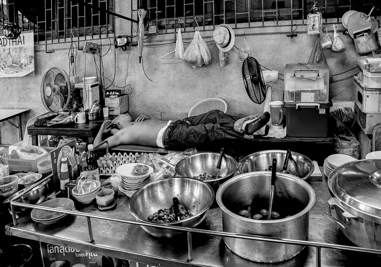 Uliczny sprzedawca jedzenia śpiący na swoim stanowisku w Bangkoku