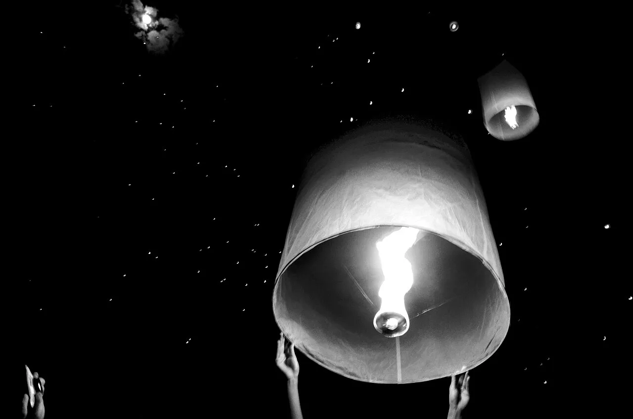 Świecący lampion unoszony w ciemne niebo podczas Yi Peng