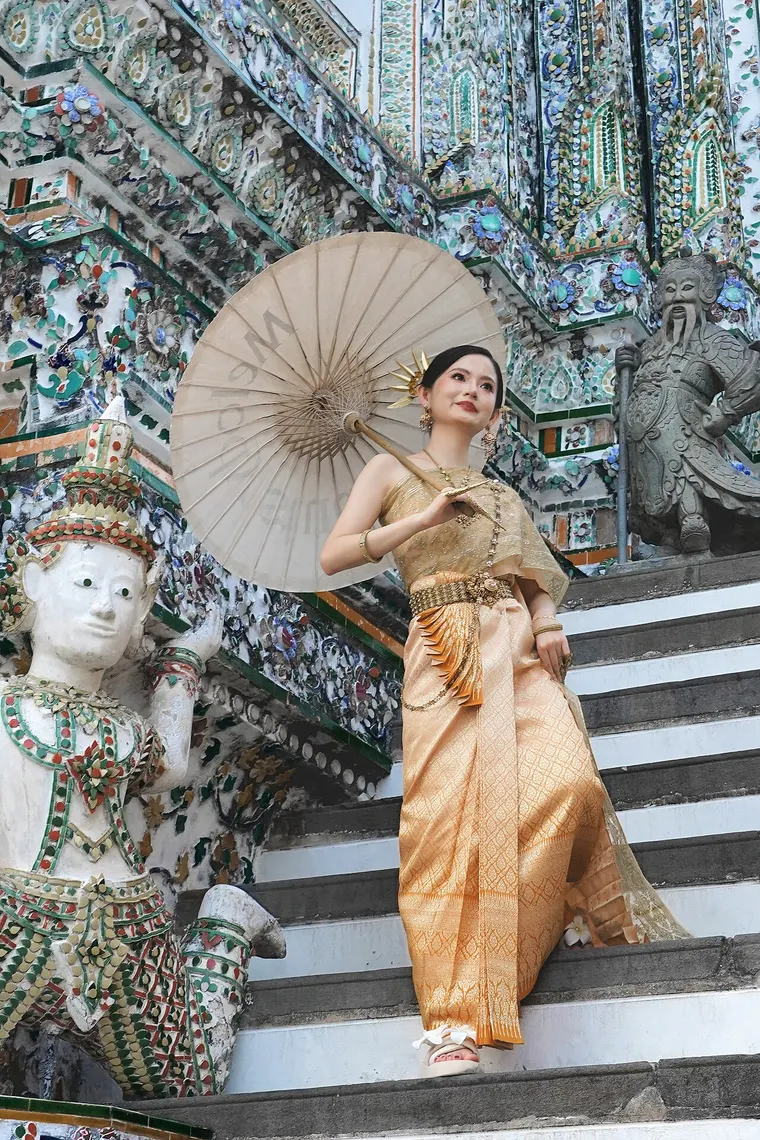 Kobieta w tradycyjnej tajskiej sukni z parasolką przy świątyni Wat Arun