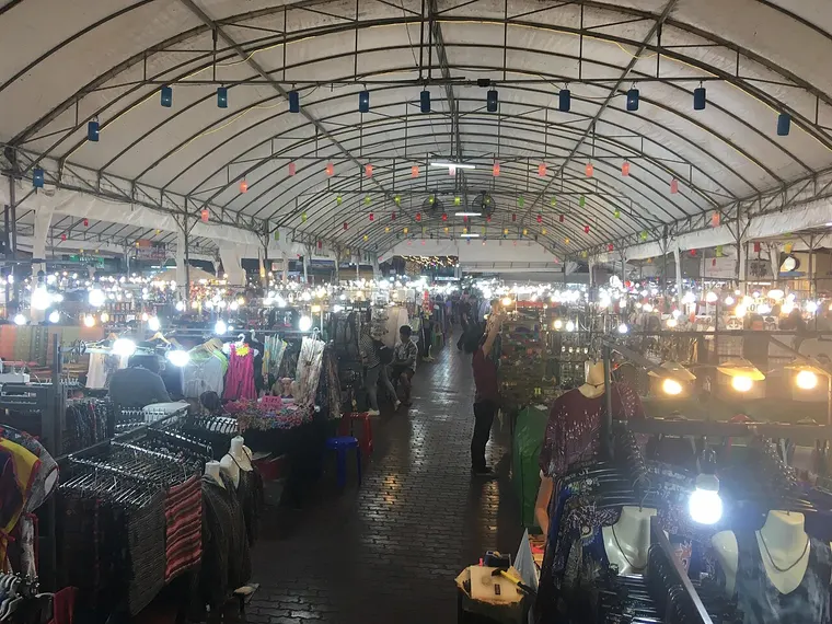 Zadaszone stragany nocnego bazaru w Chiang Mai oświetlone lampami