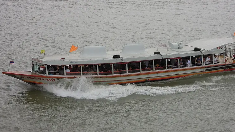 Łódź Chao Phraya Express z pomarańczową flagą płynąca po rzece Chao Phraya w Bangkoku