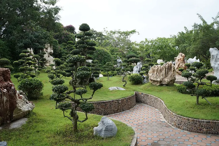 Ogród skalny z przystrzyżonymi drzewami i głazami w Million Years Stone Park w Pattayi