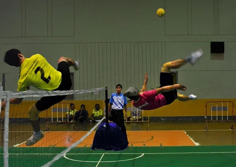 Zawodnicy sepak takraw w locie nad siatką podczas meczu