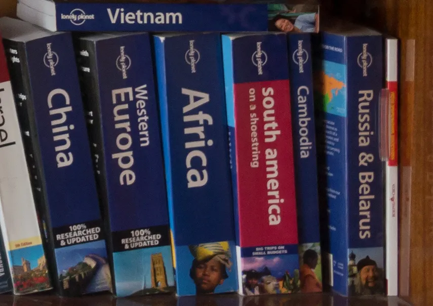 Przewodniki Lonely Planet ustawione na półce, m.in. o Chinach, Afryce i Kambodży
