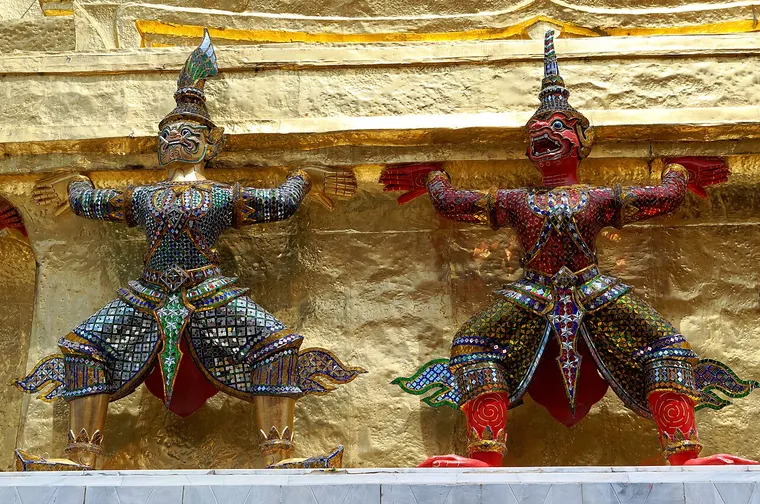 Złote posągi strażników yaksha podtrzymujące złotą chedi w Wat Phra Kaew w Bangkoku