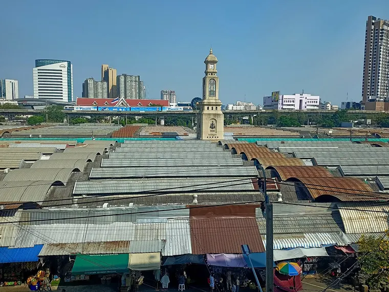 Dachy straganów targu Chatuchak i wieża zegarowa na tle wieżowców Bangkoku