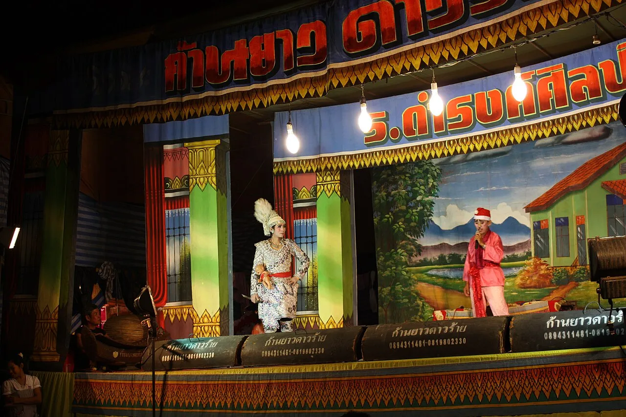 Scena teatru li-khe z aktorami w tradycyjnych strojach na tle malowanej dekoracji