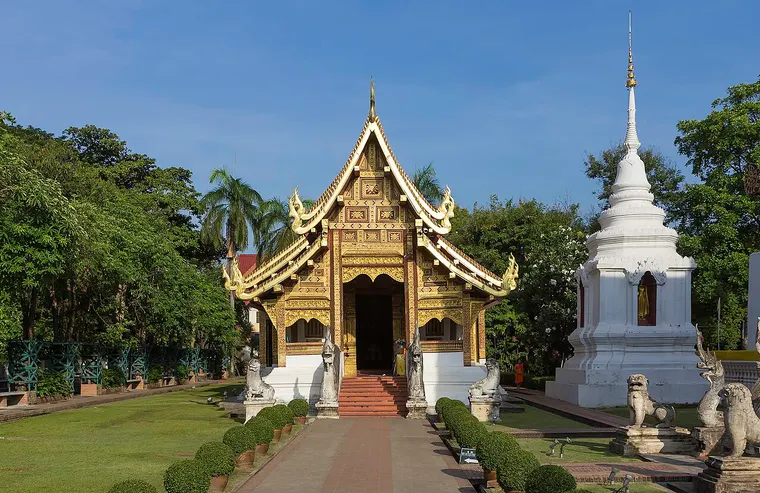 Złocona kaplica i biała stupa w świątyni Wat Phra Singh w Chiang Mai
