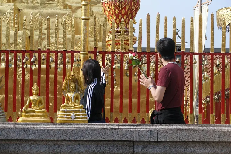 Wierni modlący się przy pozłacanej chedi Wat Phra That Doi Suthep